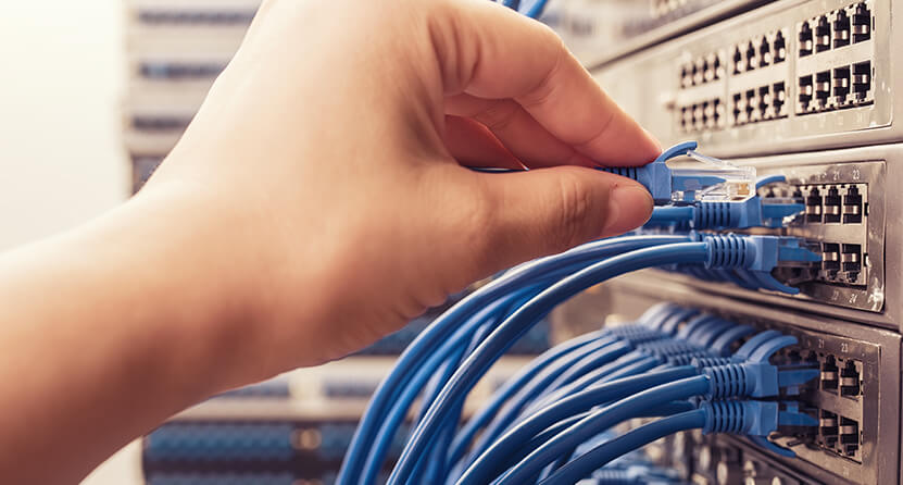 An Opus Interactive blog image about Cloud Migration, it is a closeup of a hand connecting a cable to a server.