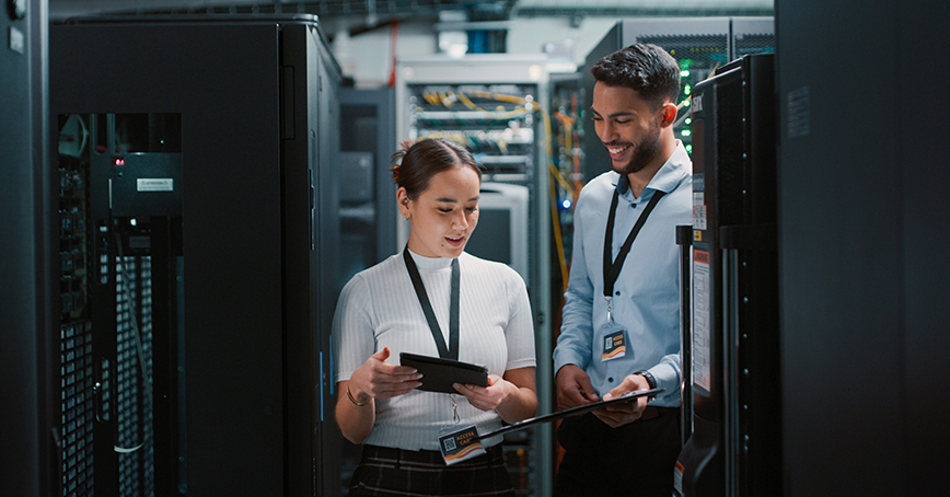 An Opus Interactive blog post image of international women in Engineering, it shows two technicians in a server room, one is a man, and one is a woman.