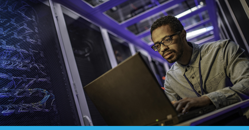A blog post image depicting a male technician accessing a server with a laptop in a server room.